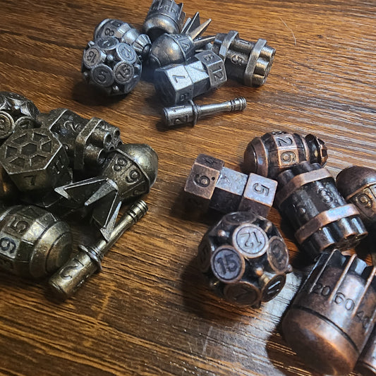 Three metal bomb dice sets in brass, iron and copper finishes