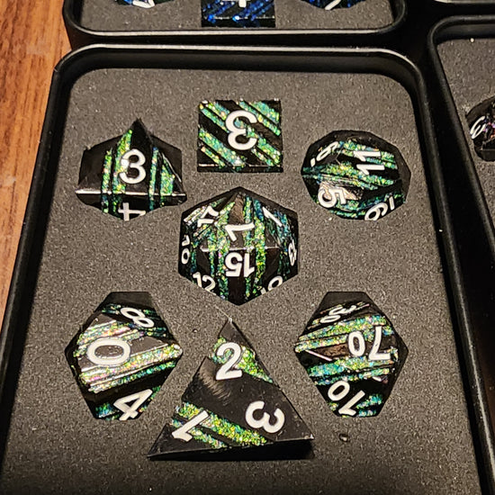 Jadehold black and green striped seven-piece metal dice set in a padded box
