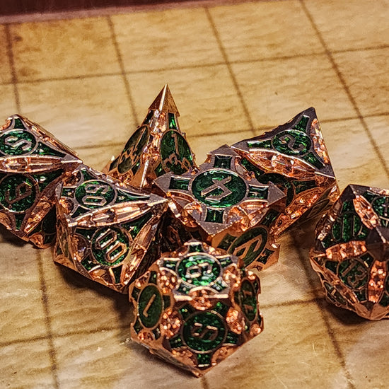 Copper and green seven-piece metal dice set with sculpted geometric details