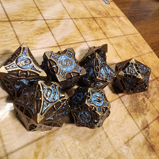 Antique bronze and light blue seven-piece metal dice set with sculpted geometric details