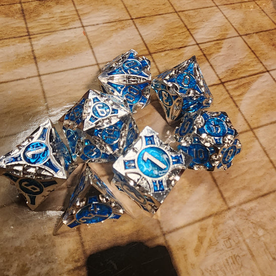 Silver and blue seven-piece metal dice set with sculpted geometric details