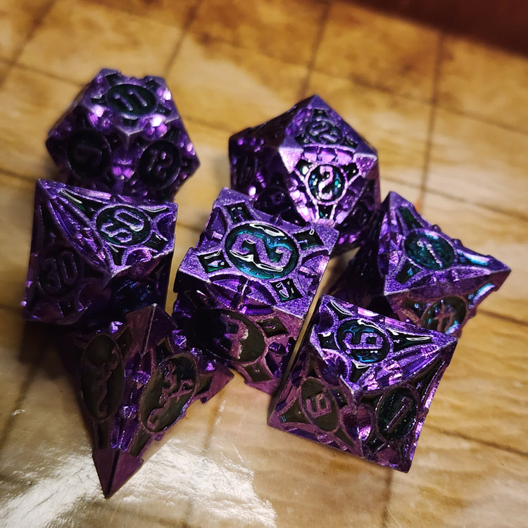 Purple and teal seven-piece metal dice set with sculpted geometric details