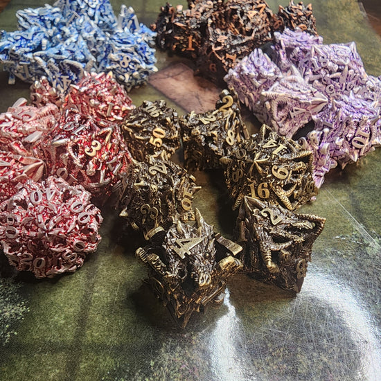 Spiky metal dragon dice sets in brass, copper, silver and blue, silver and purple, and silver and red finishes