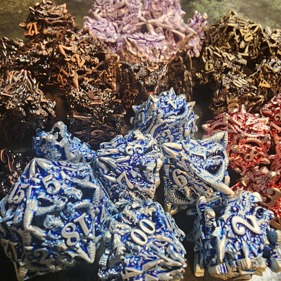 Close-up of silver and blue dragon faces and spikes with other metal dice finishes behind