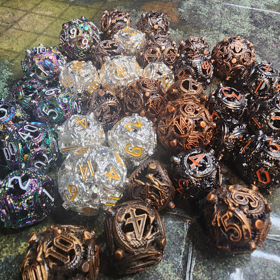 Five finishes of Wyrmseal Relics hollow metal dice with coiling scale-textured details