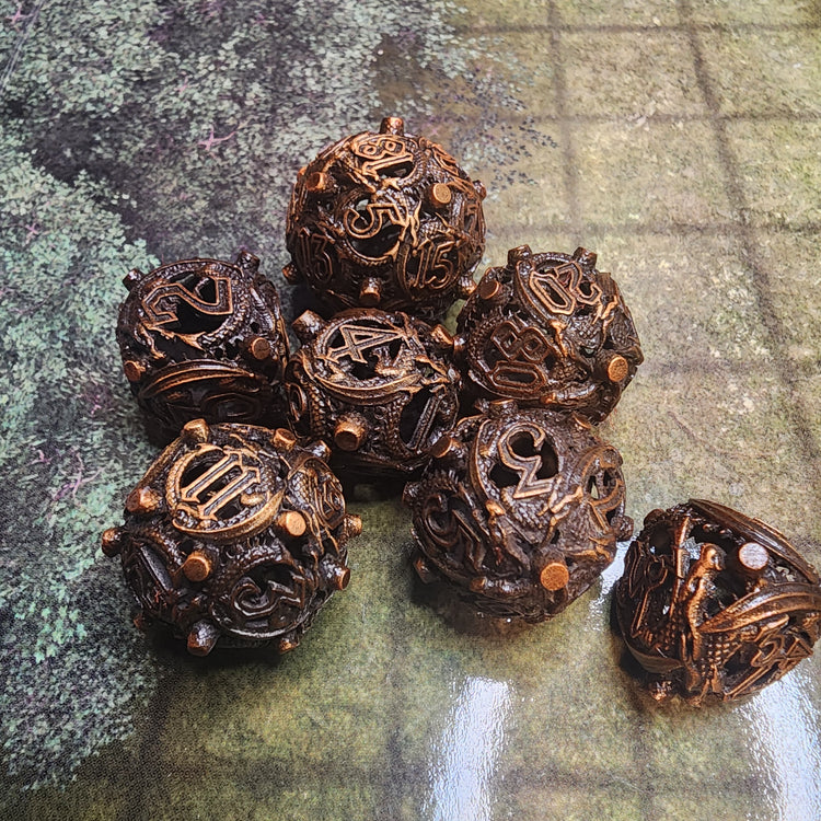Burned brass hollow metal dice set with winding scale-textured details