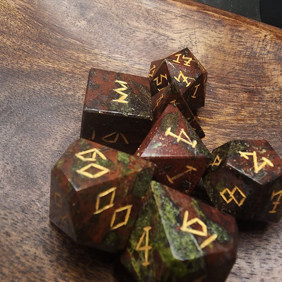Angled view of Dragonblood Jasper dice on a wooden surface