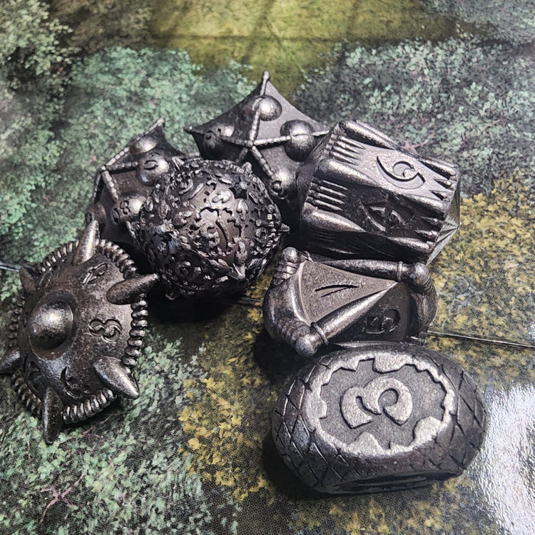 Iron finish seven-piece metal dice set with sculpted artifact shapes and dark recessed details
