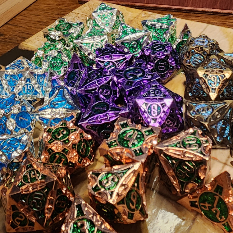 Alternate view of five finishes of Monuments of the Lost Sands metal dice arranged on a tan grid surface