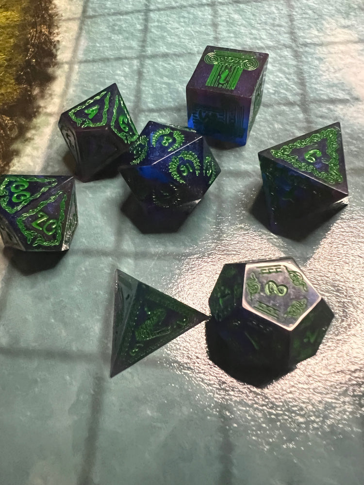 Close-up of sparkling blue-purple sharp resin dice with green mythology-inspired designs