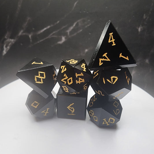 Complete seven-piece black Obsidian dice set with gold-colored numbering on a white display