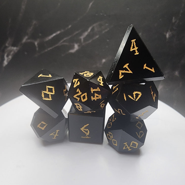 Complete seven-piece black Obsidian dice set with gold-colored numbering on a white display