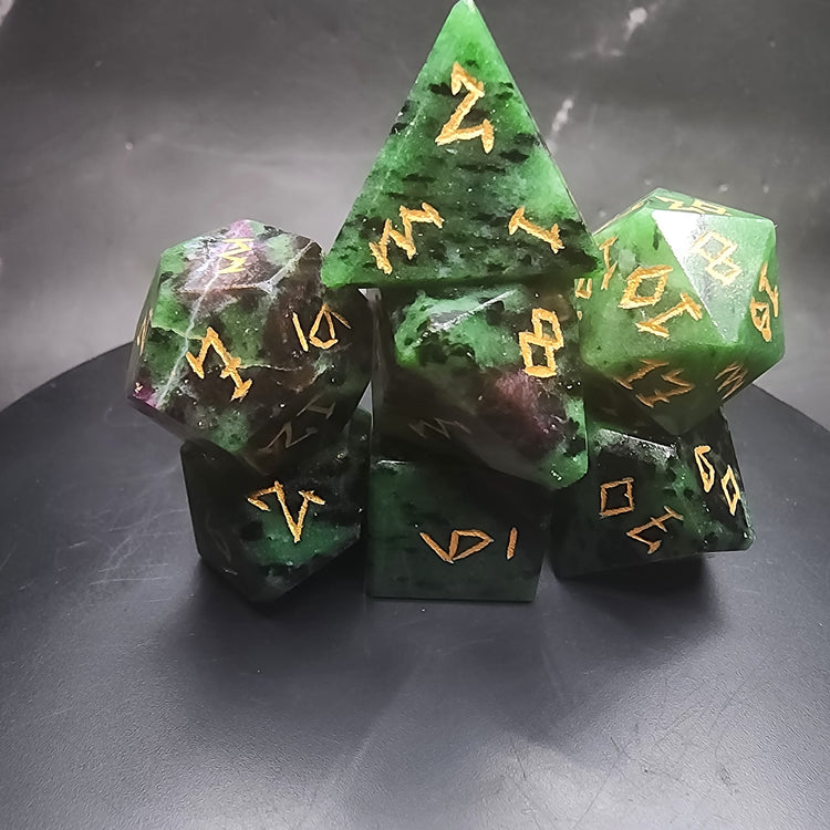 Stacked Ruby Zoisite polyhedral dice showing green and violet-red patterns with gold-colored numbers