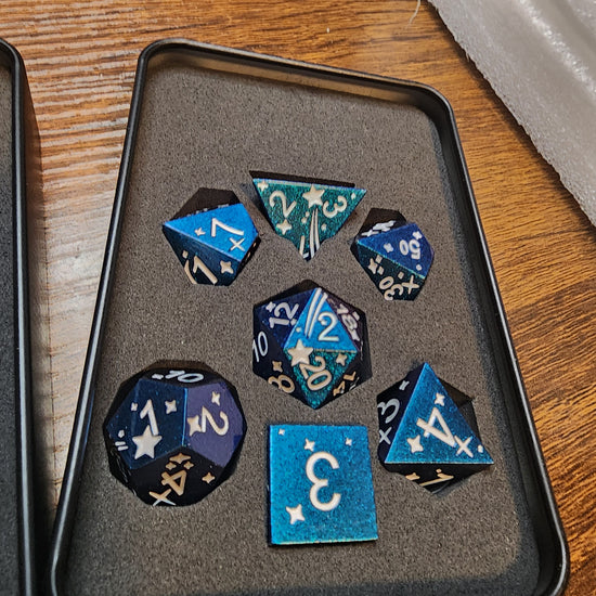 Blue and purple celestial seven-piece metal dice set in its tin