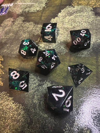 Close view of green reflective inclusions in dark resin RPG dice